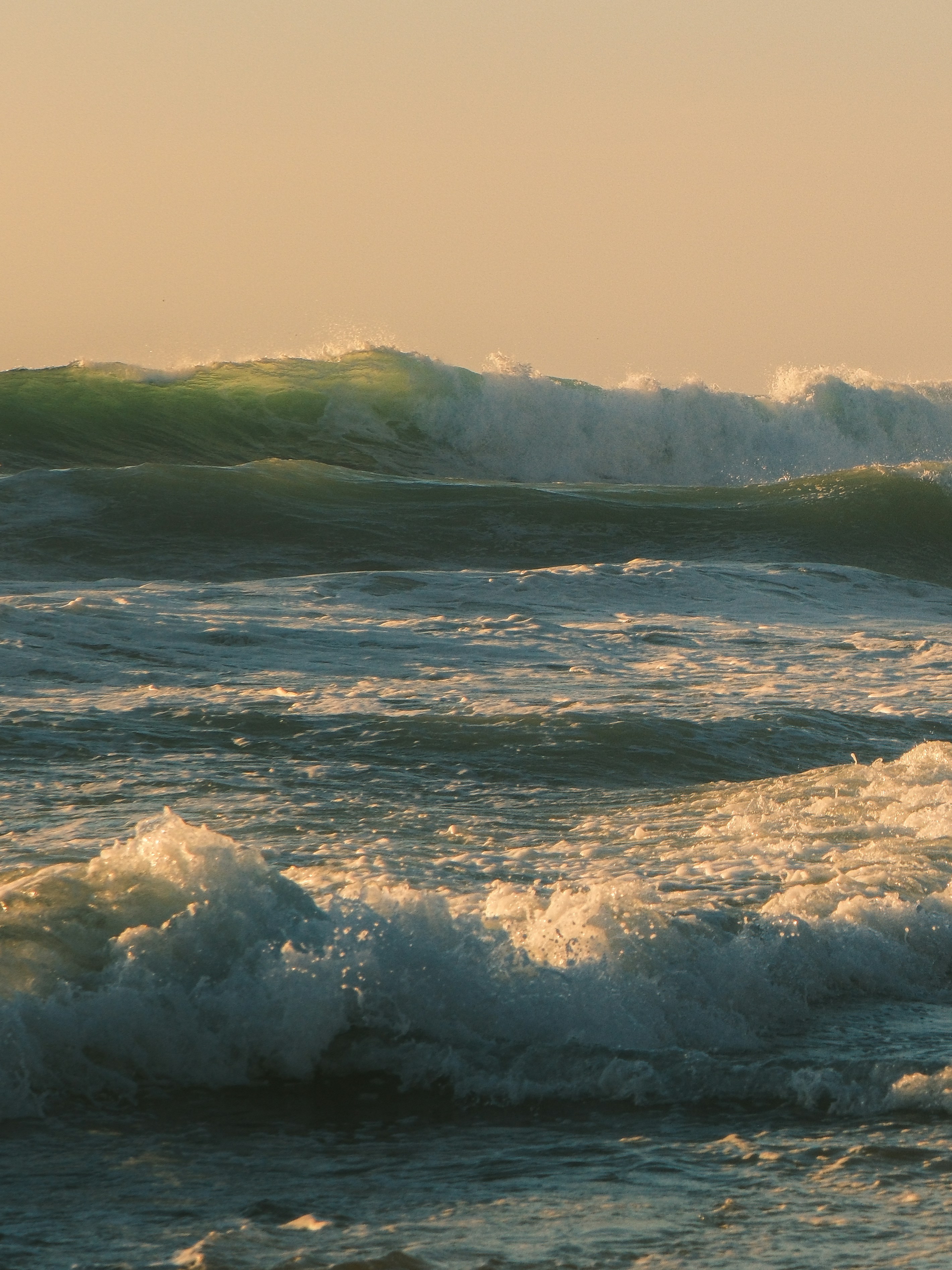 Ocean waves crashing under a warm sky